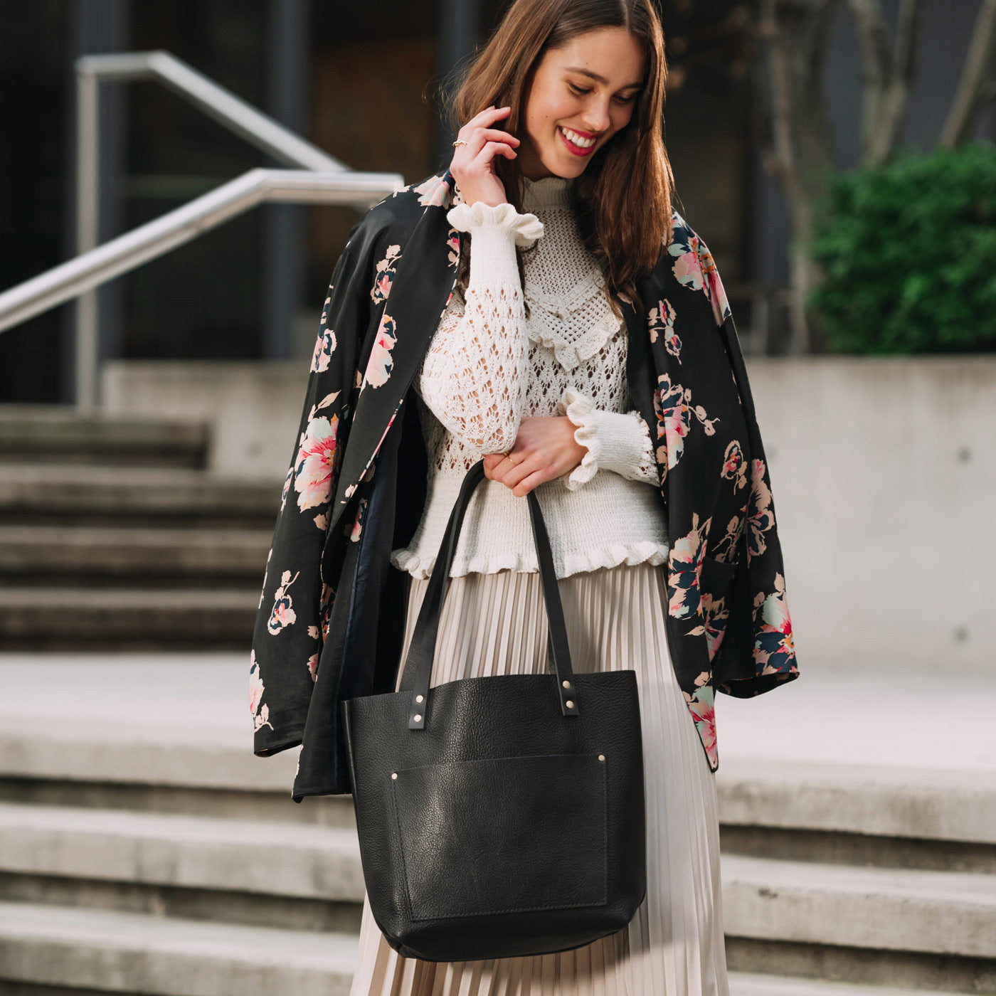 Pebbled--black | Model wearing larger leather tote bag with sturdy bridle handles and front pocket outside