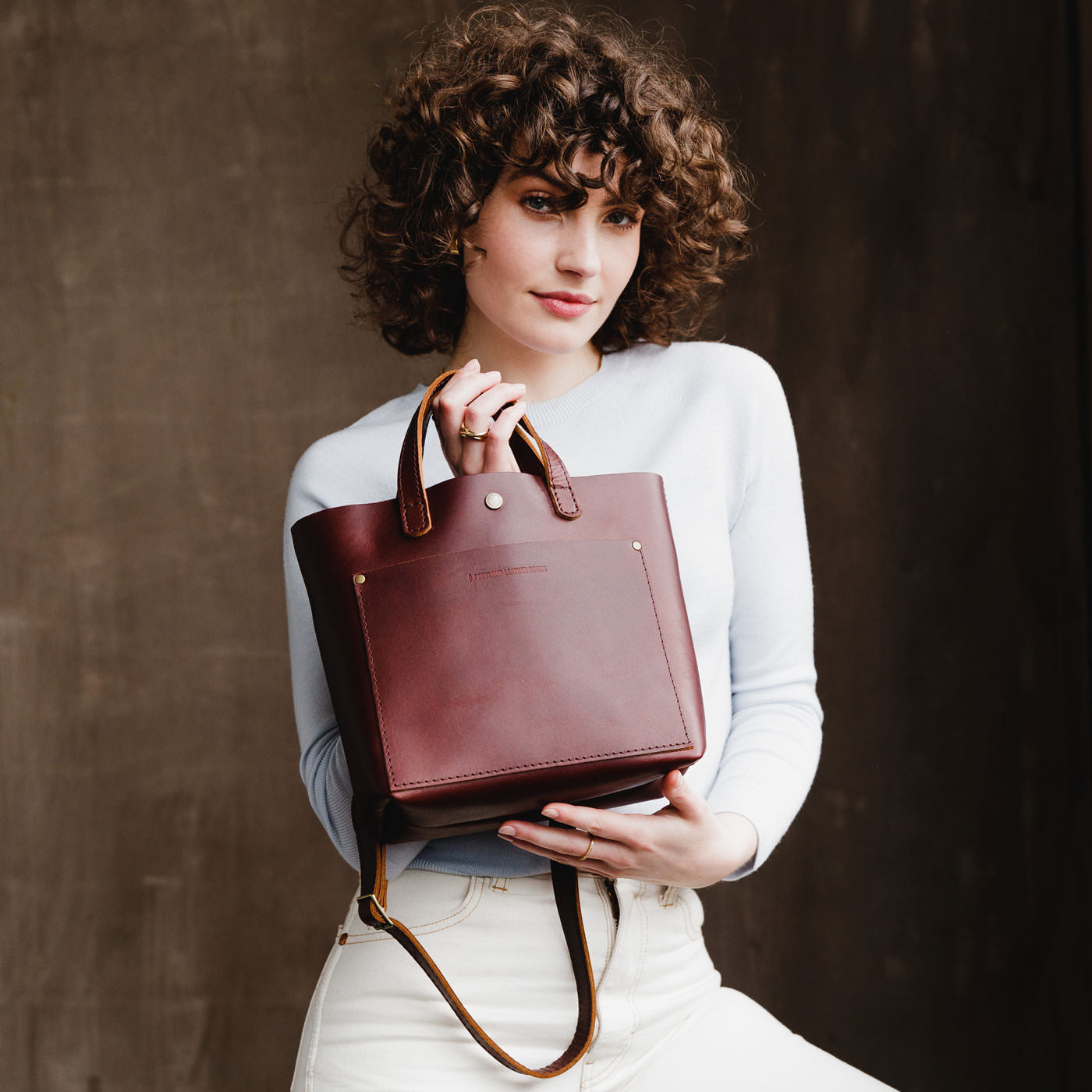 Cognac*Classic | Model holding crossbody tote bag with snap closure and front pocket