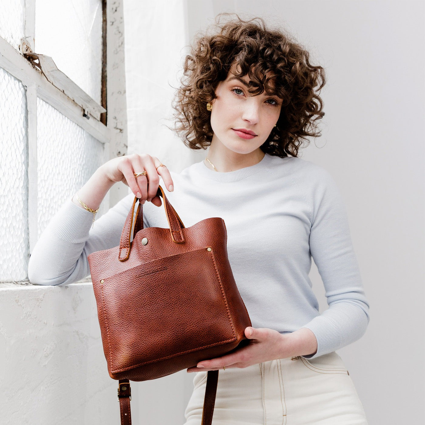 Nutmeg Classic | Model holding crossbody tote bag with snap closure and front pocket