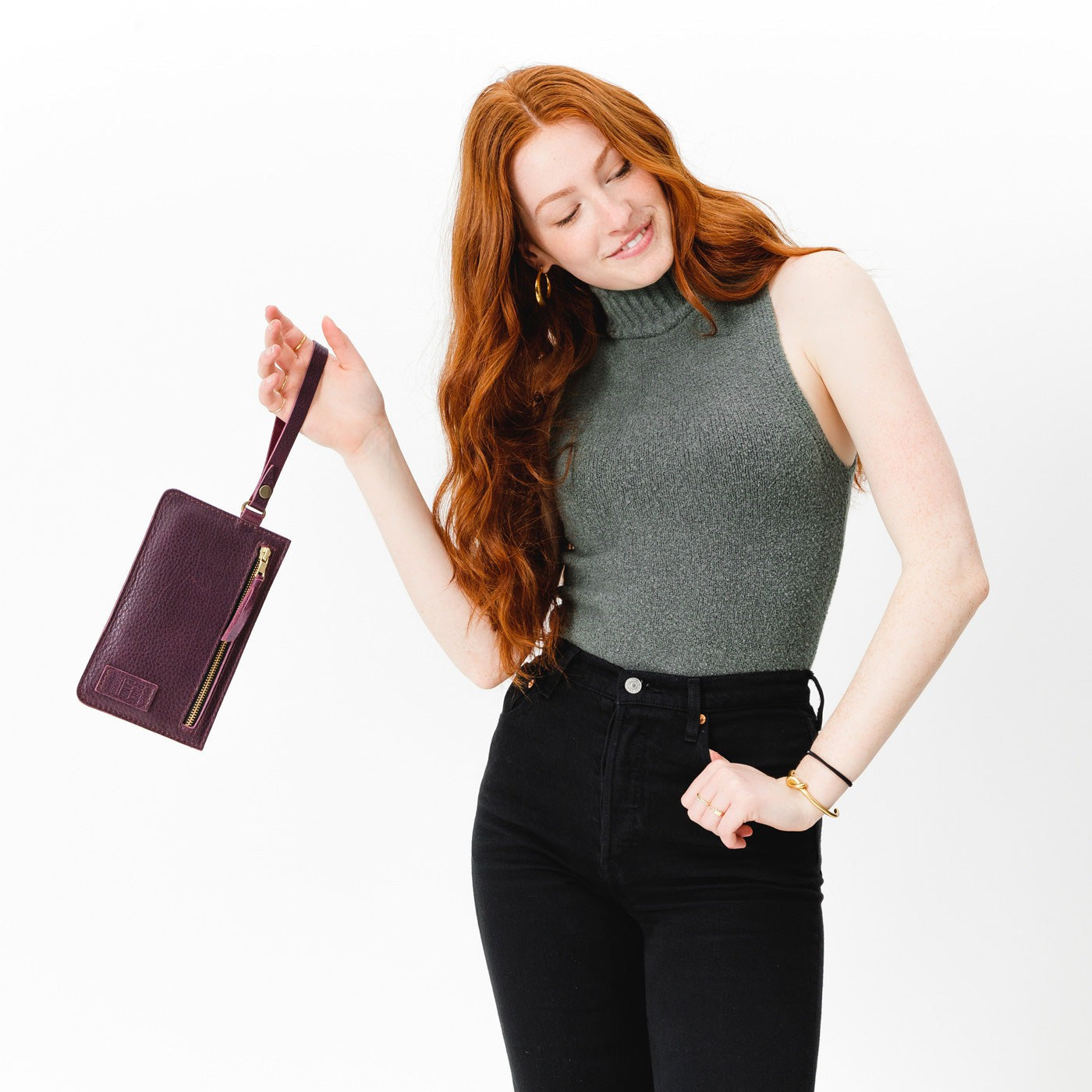 Plum | Model holding flat leather pouch with zipper and wristlet