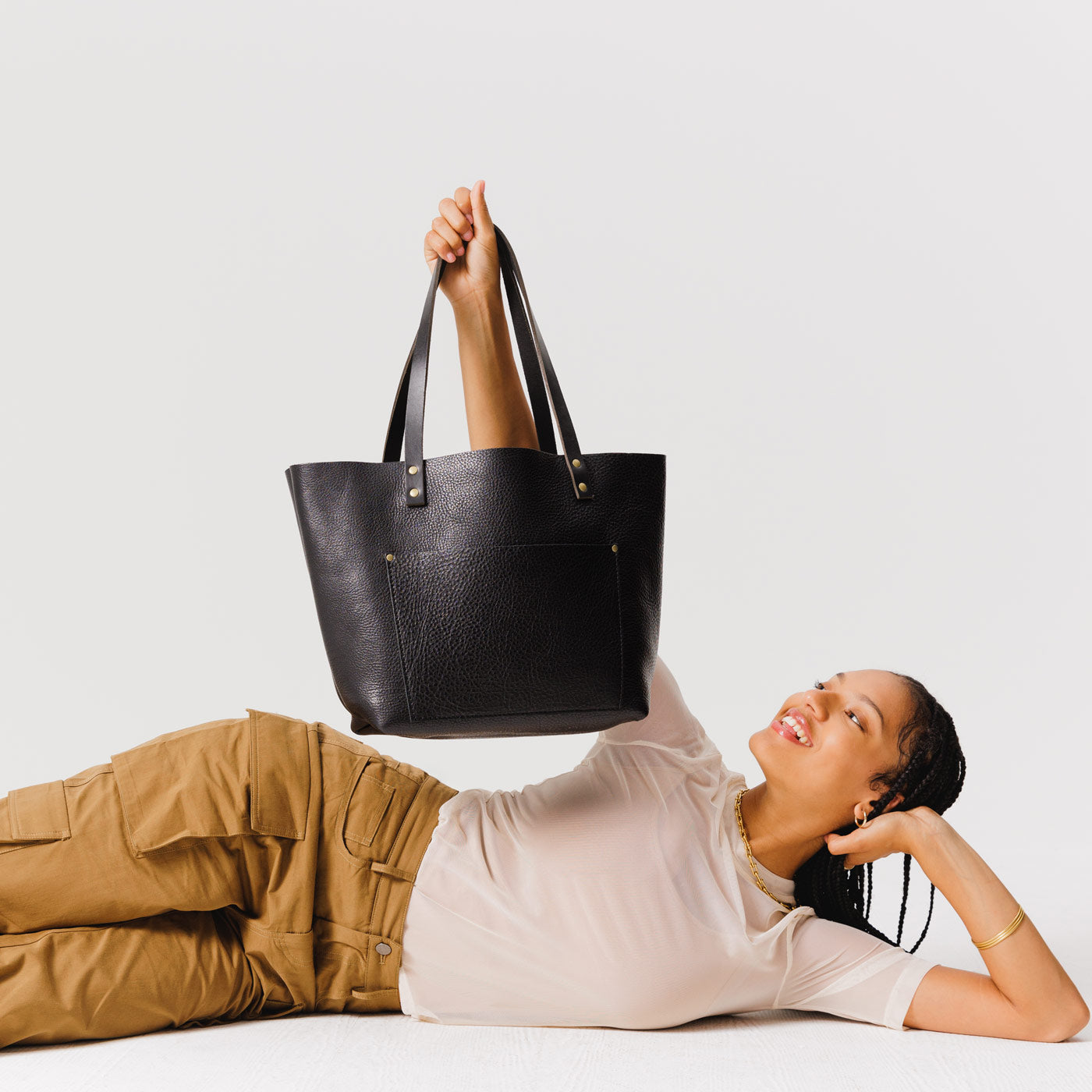 Pebbled--black*Classic | Model holding large leather tote bag with sturdy bridle handles and front pocket