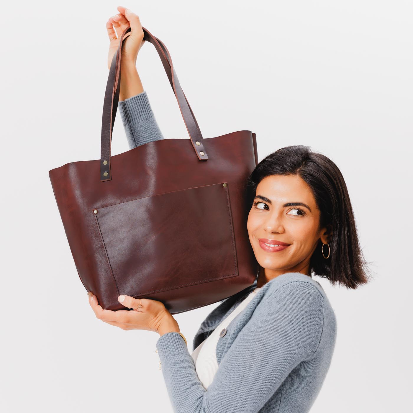 Cognac*Classic | Model holding large leather tote bag with sturdy bridle handles and front pocket