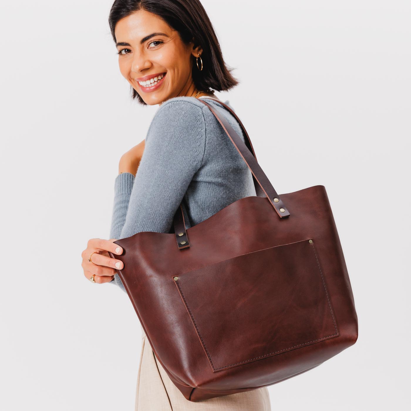 Cognac*Classic  | Model holding large leather tote bag with sturdy bridle handles and front pocket