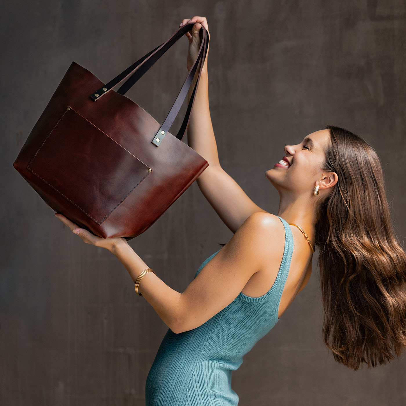 Cognac*Classic | Model holding large leather tote bag with sturdy bridle handles and front pocket