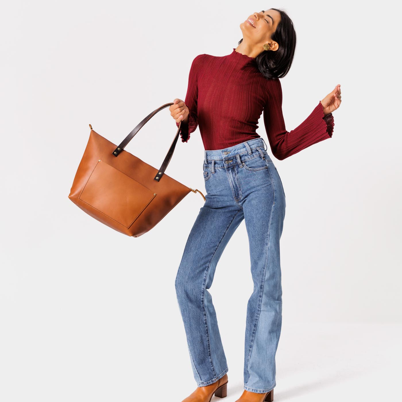 Honey Zipper | Model holding large zipper leather tote bag with sturdy bridle handles and front pocket