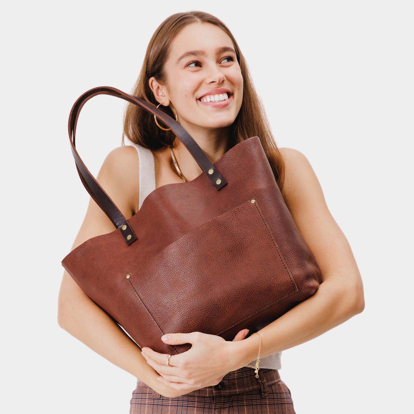 Nutmeg Classic | Model holding large leather tote bag with sturdy bridle handles and front pocket