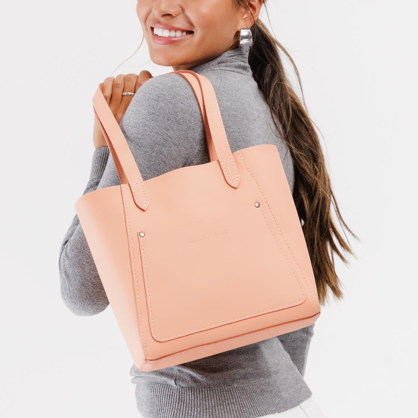 Mamey Small | Model holding dual shoulder strap tote bag with an exterior pocket