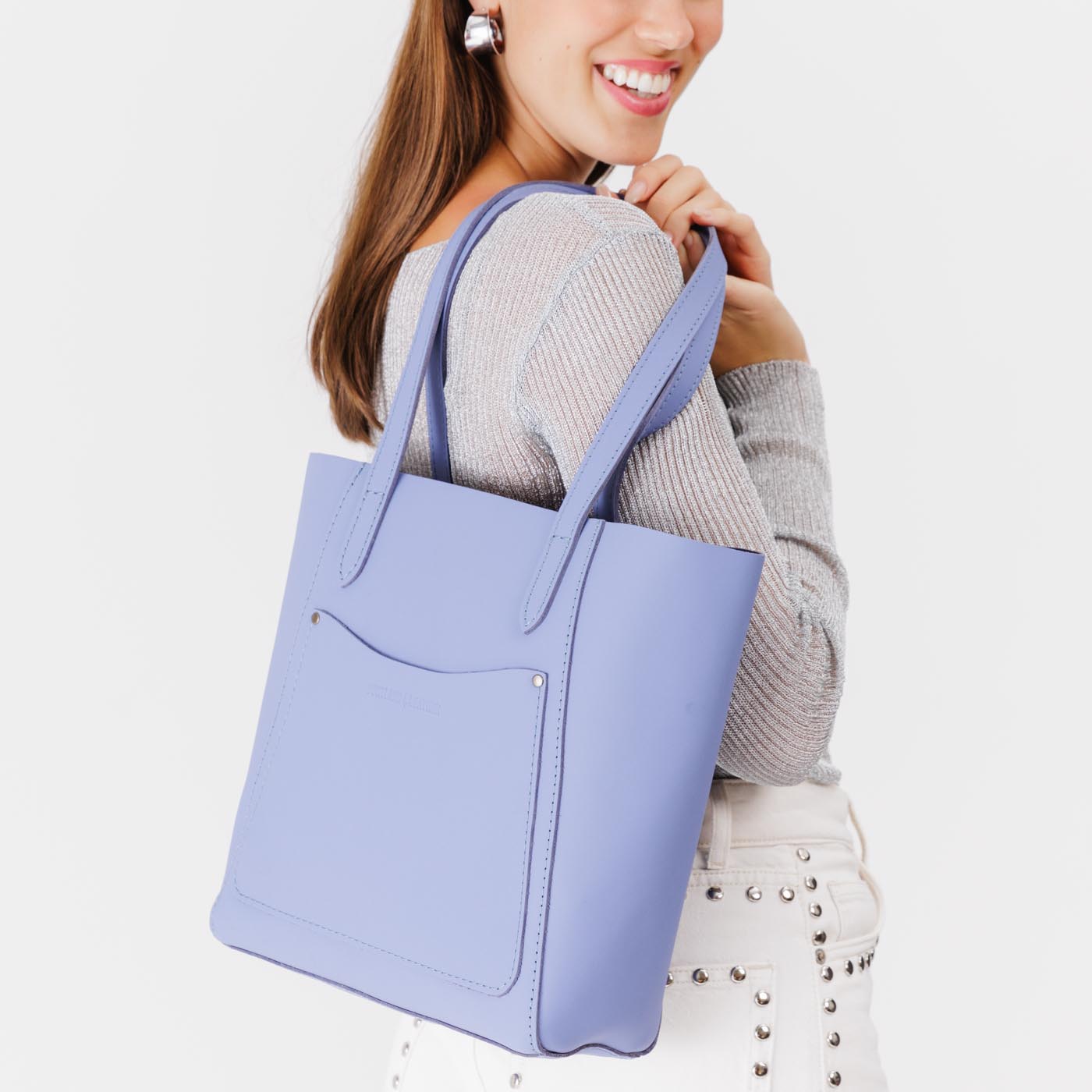 Jacaranda Large | Model holding dual shoulder strap tote bag with an exterior pocket