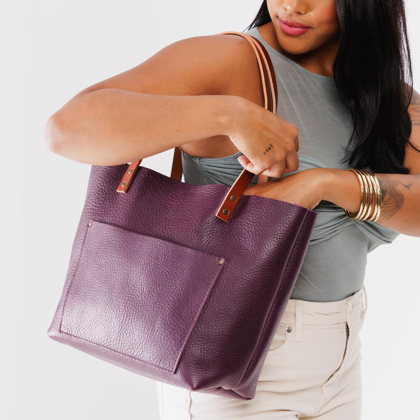 Plum Classic | Model holding large leather tote bag with sturdy bridle handles and front pocket