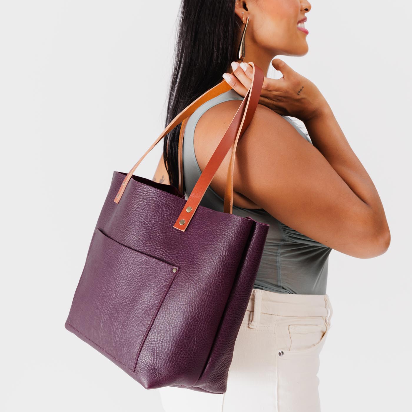 Plum Classic | Model holding large leather tote bag with sturdy bridle handles and front pocket