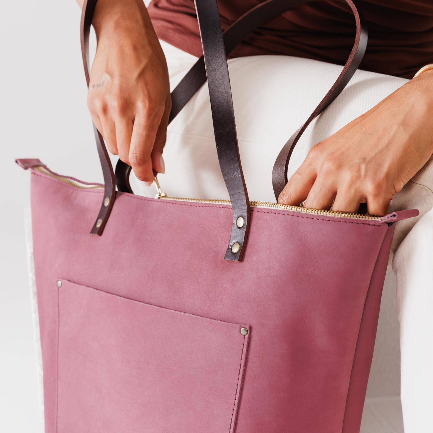 Foxglove*Zipper | Model holding large leather tote bag with sturdy bridle handles and front pocket