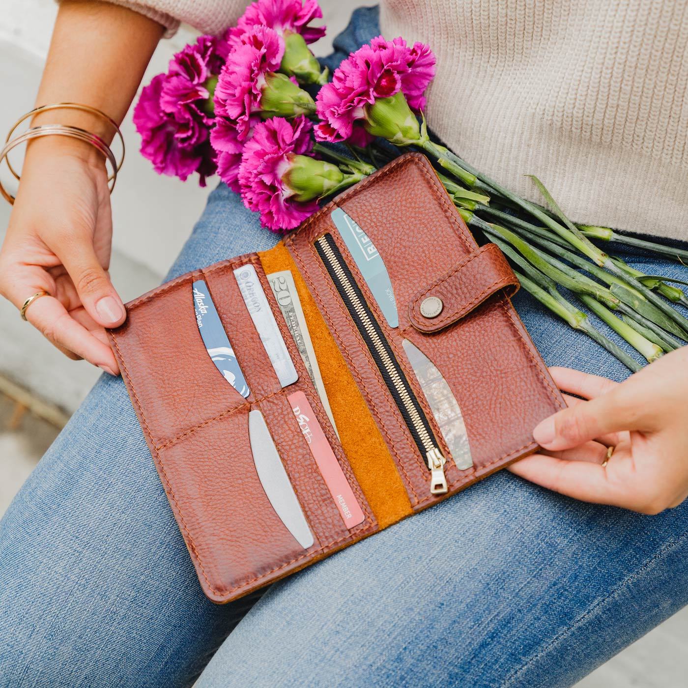 Nutmeg | Model holding flowers and leather wallet with snap open