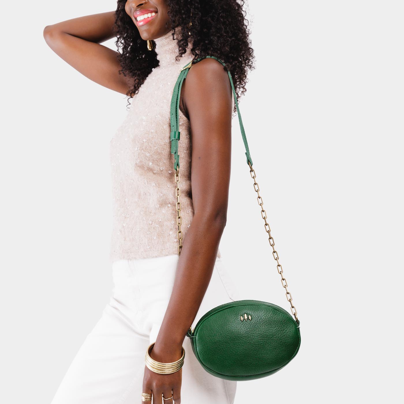 Bacalar | Model wearing oval leather purse with metal crossbody chain strap and adjustable leather shoulder guard