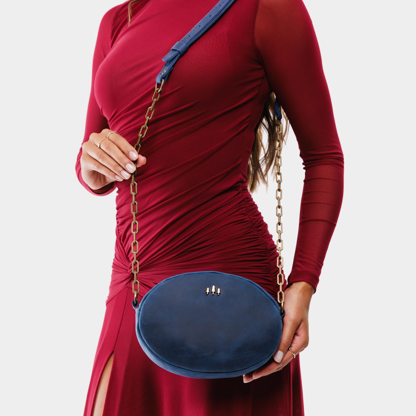 Deep Water | Model wearing oval leather purse with metal crossbody chain strap and adjustable leather shoulder guard