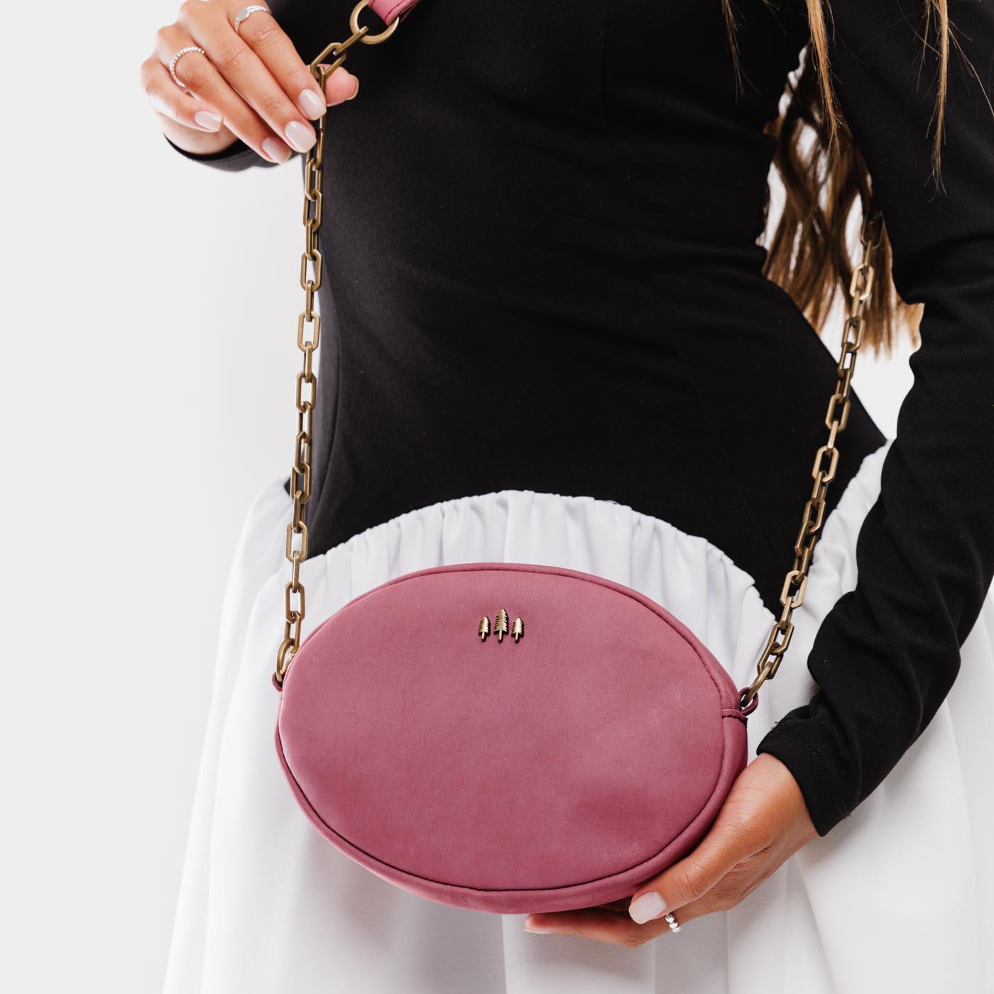 Foxglove | Model wearing oval leather purse with metal crossbody chain strap and adjustable leather shoulder guard