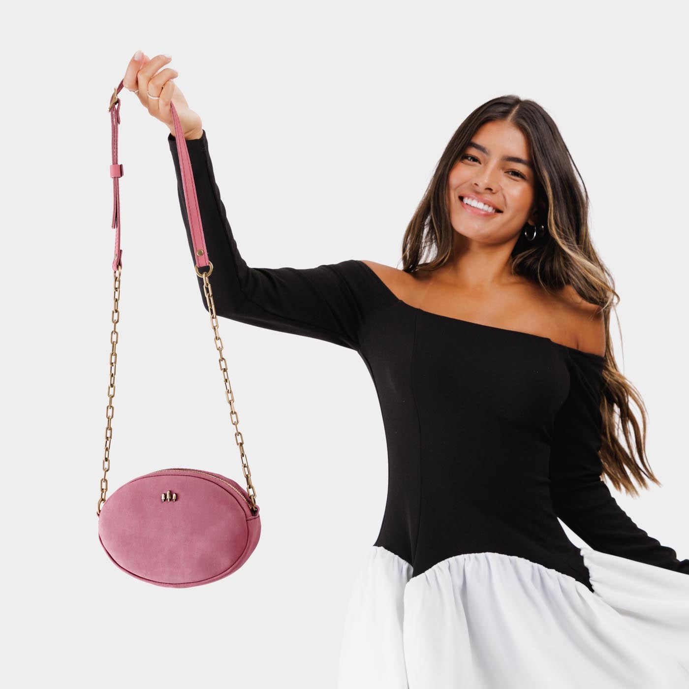 Foxglove | Model wearing oval leather purse with metal crossbody chain strap and adjustable leather shoulder guard