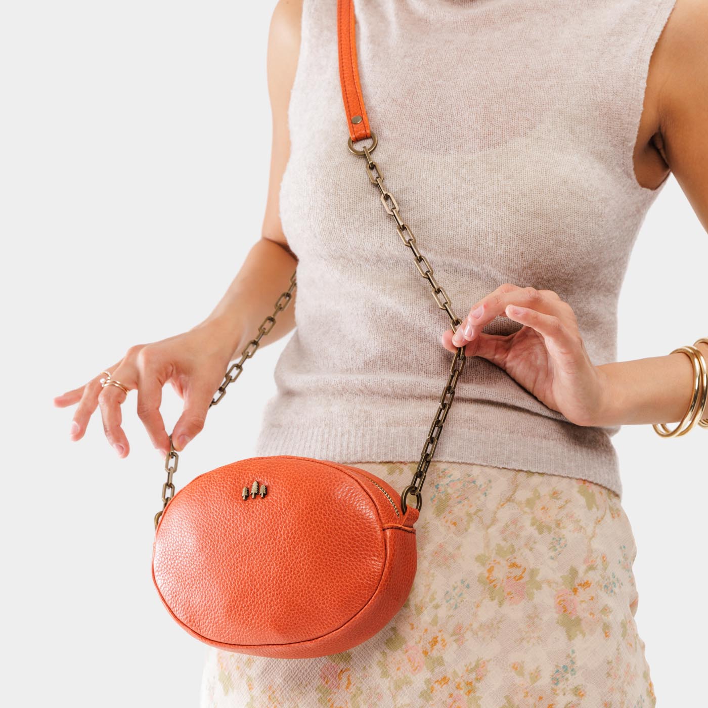 Koi | Model wearing oval leather purse with metal crossbody chain strap and adjustable leather shoulder guard