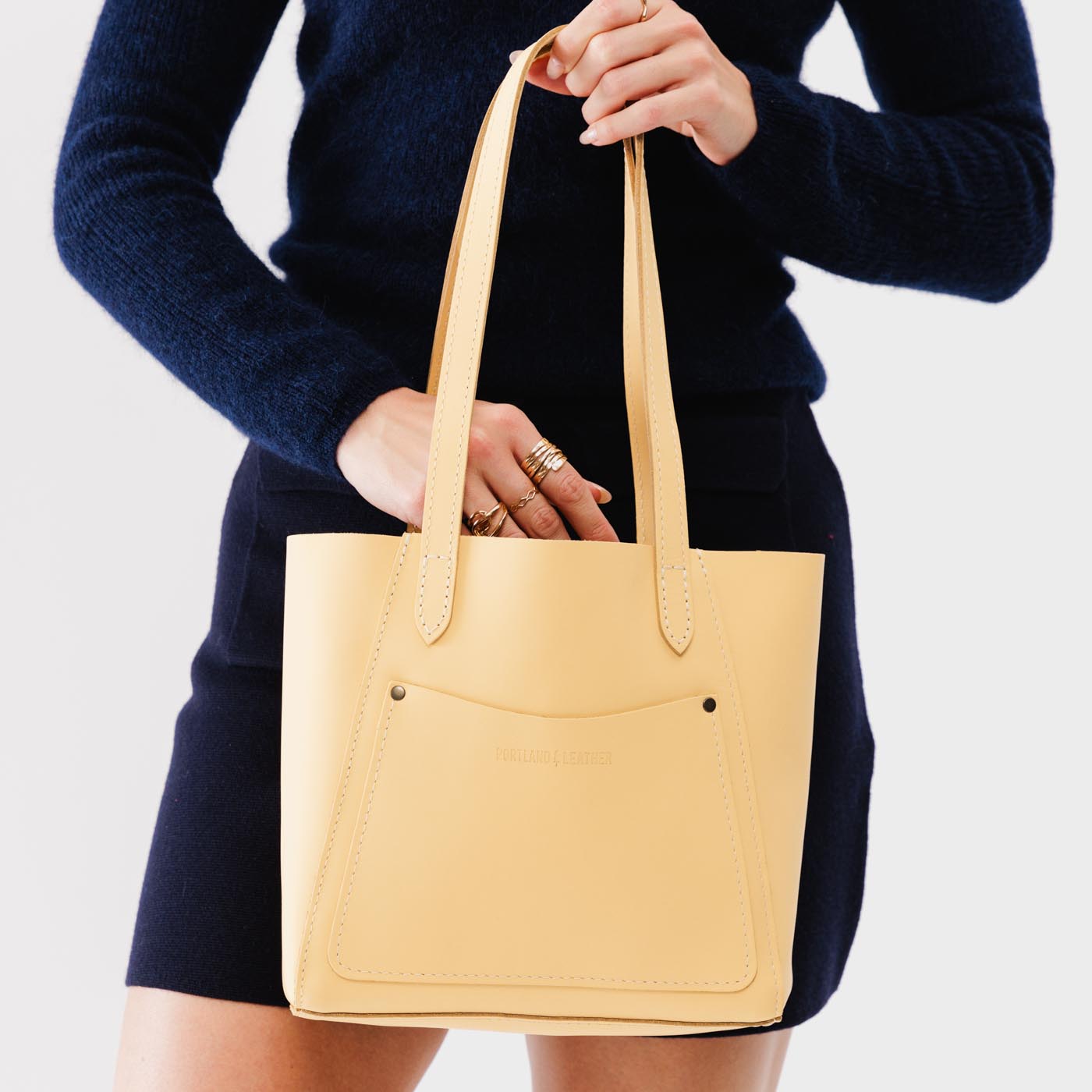 Vanilla*Small | Model holding dual shoulder strap tote bag with an exterior pocket