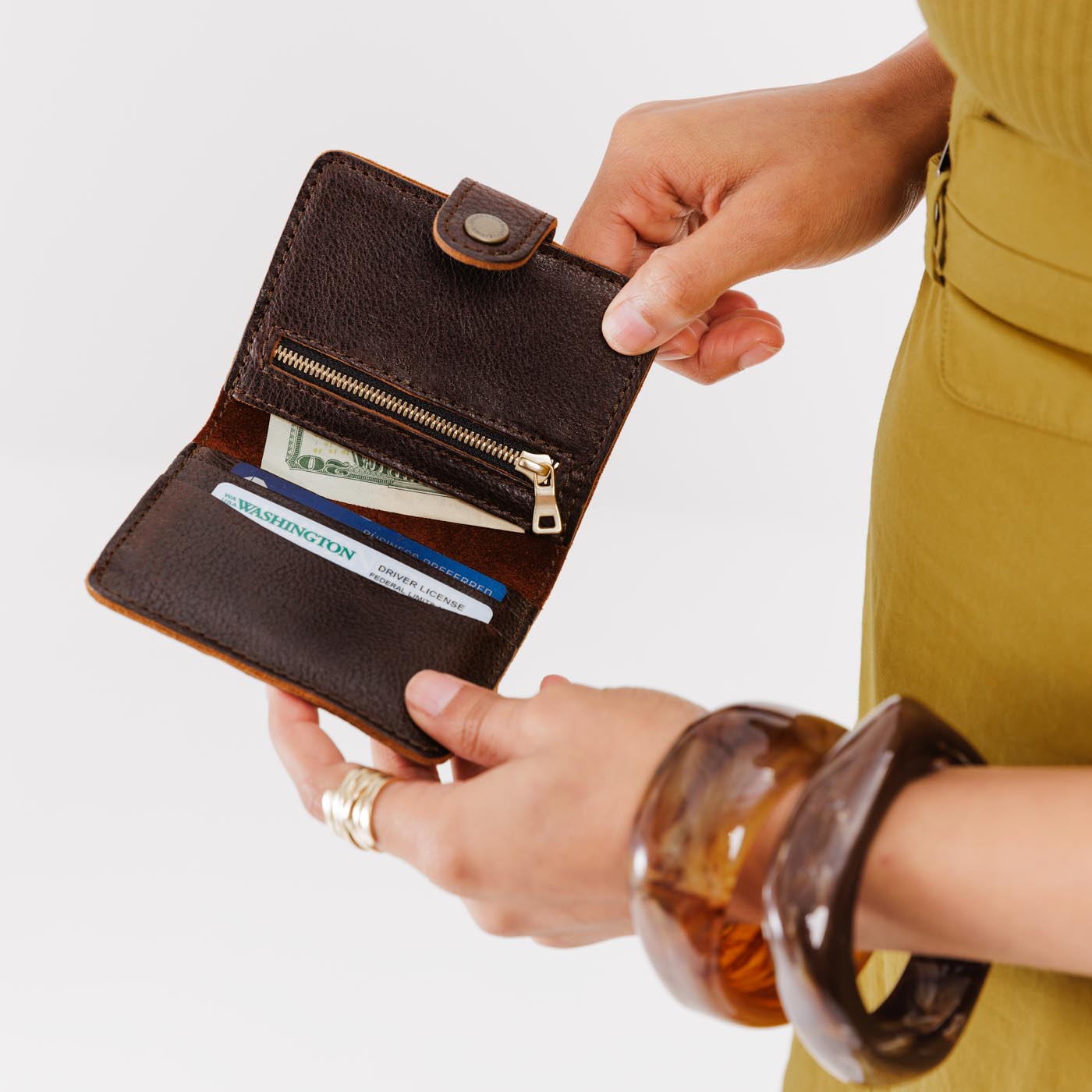 Coldbrew | Model holding small leather bifold wallet with snap open