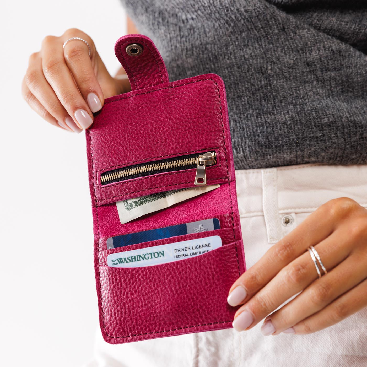 Cosmo | Model holding small leather bifold wallet with snap open