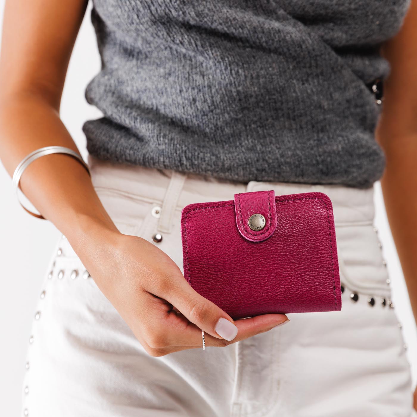 Cosmo | Model holding small leather bifold wallet with snap closed