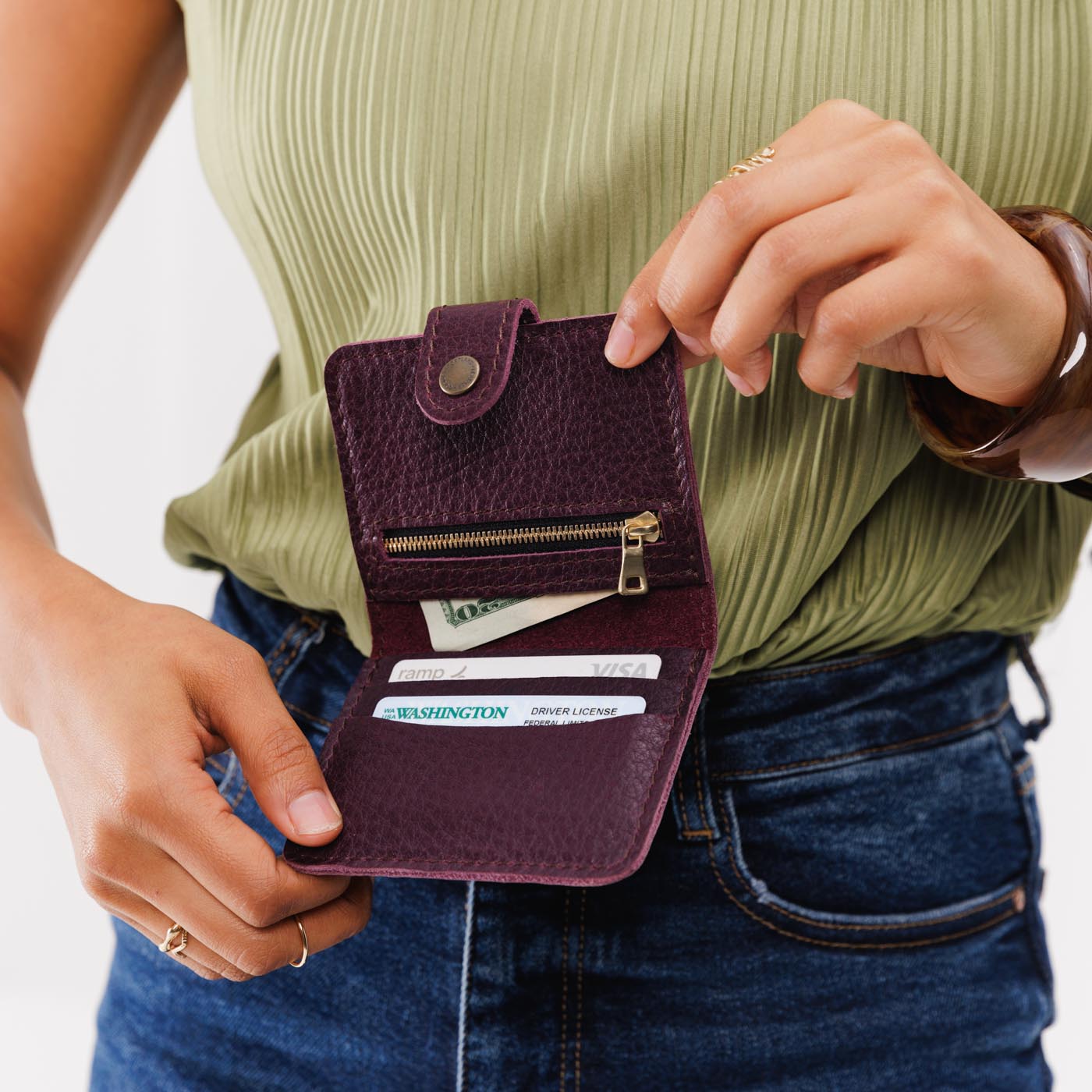 Plum | Model holding small leather bifold wallet with snap open