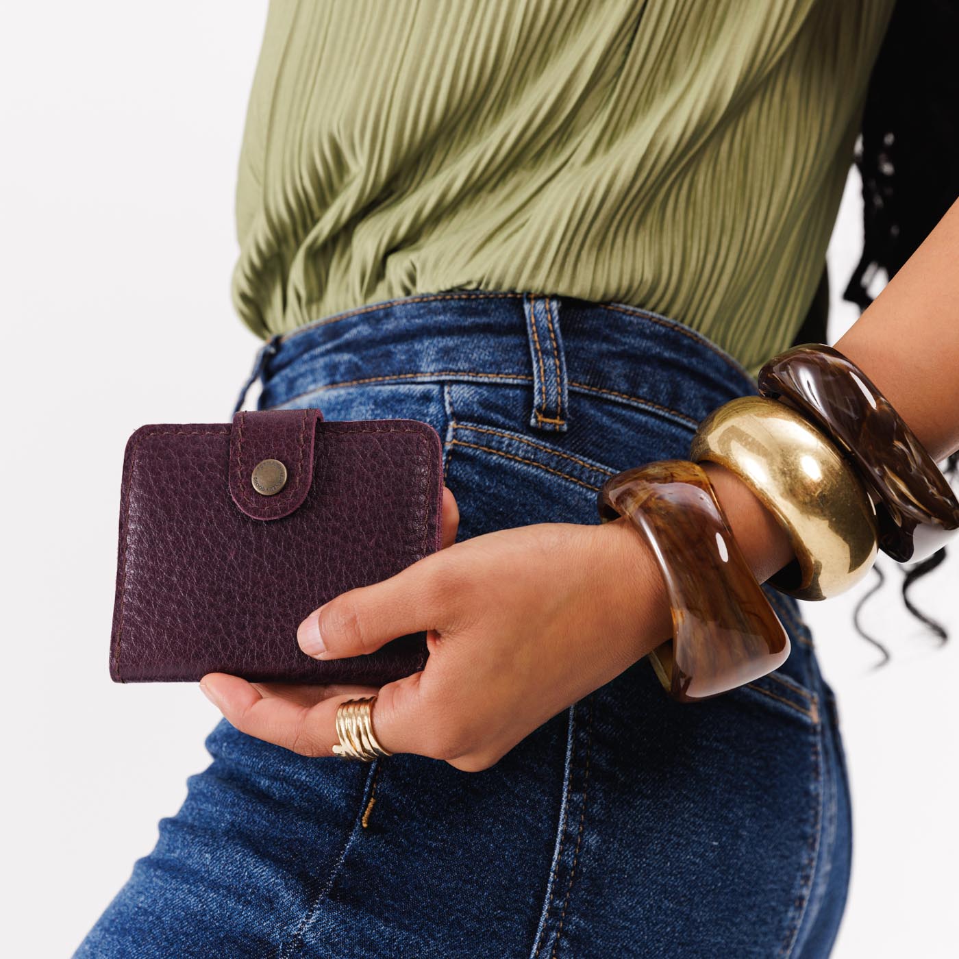 Plum | Model holding small leather bifold wallet with snap closed