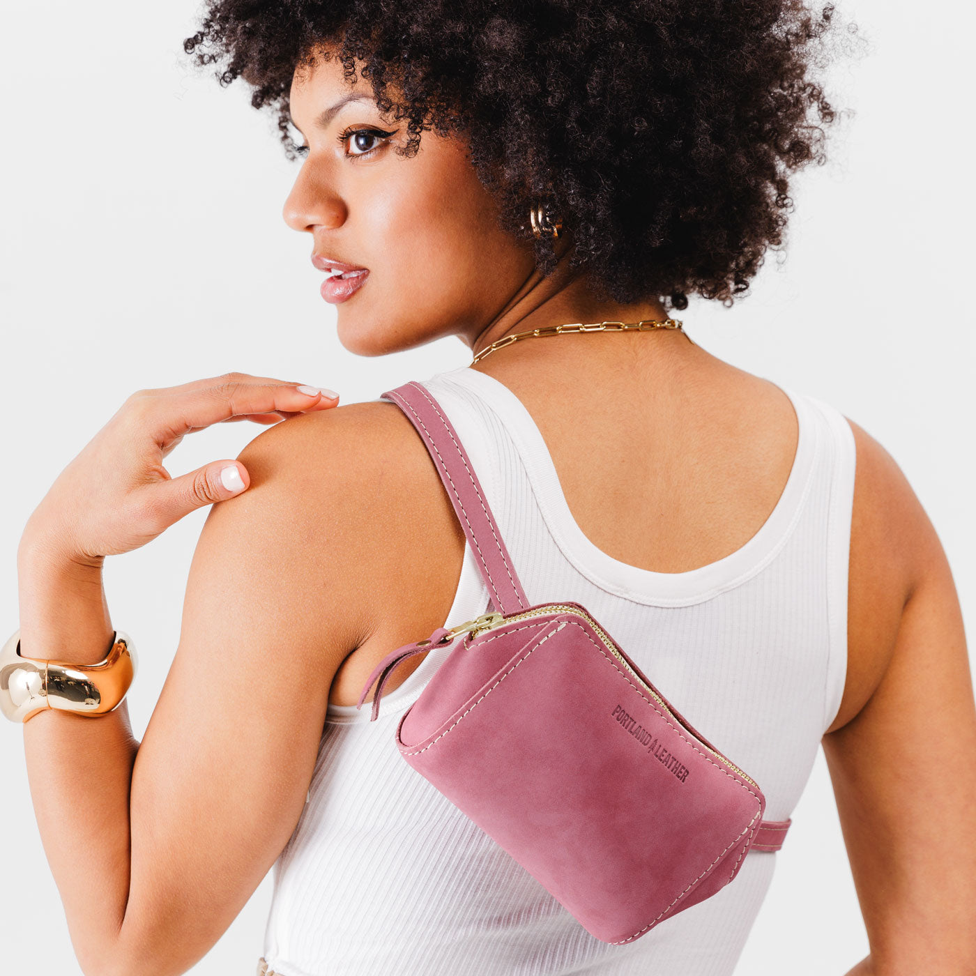 Foxglove | Close up of model wearing petite bag with top zipper closure and adjustable belt strap on the back