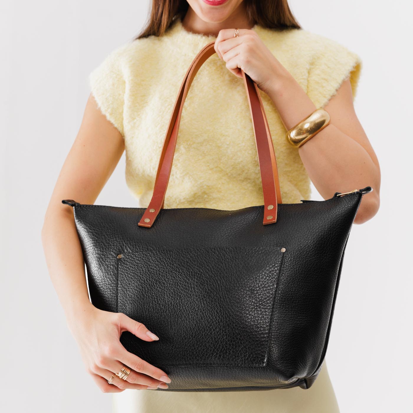 Pebbled--black*Zipper | Model holding large leather tote bag with sturdy bridle handles and front pocket