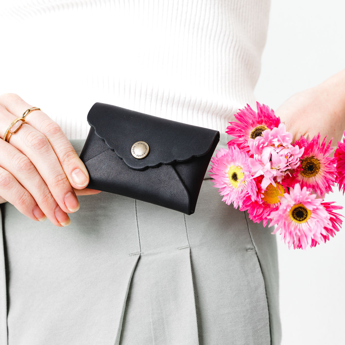 Black | Model holding flowers and small leather wallet with scalloped edge