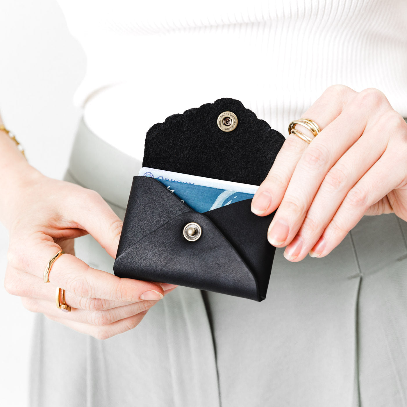 Black | Model holding small leather wallet with scalloped edge open