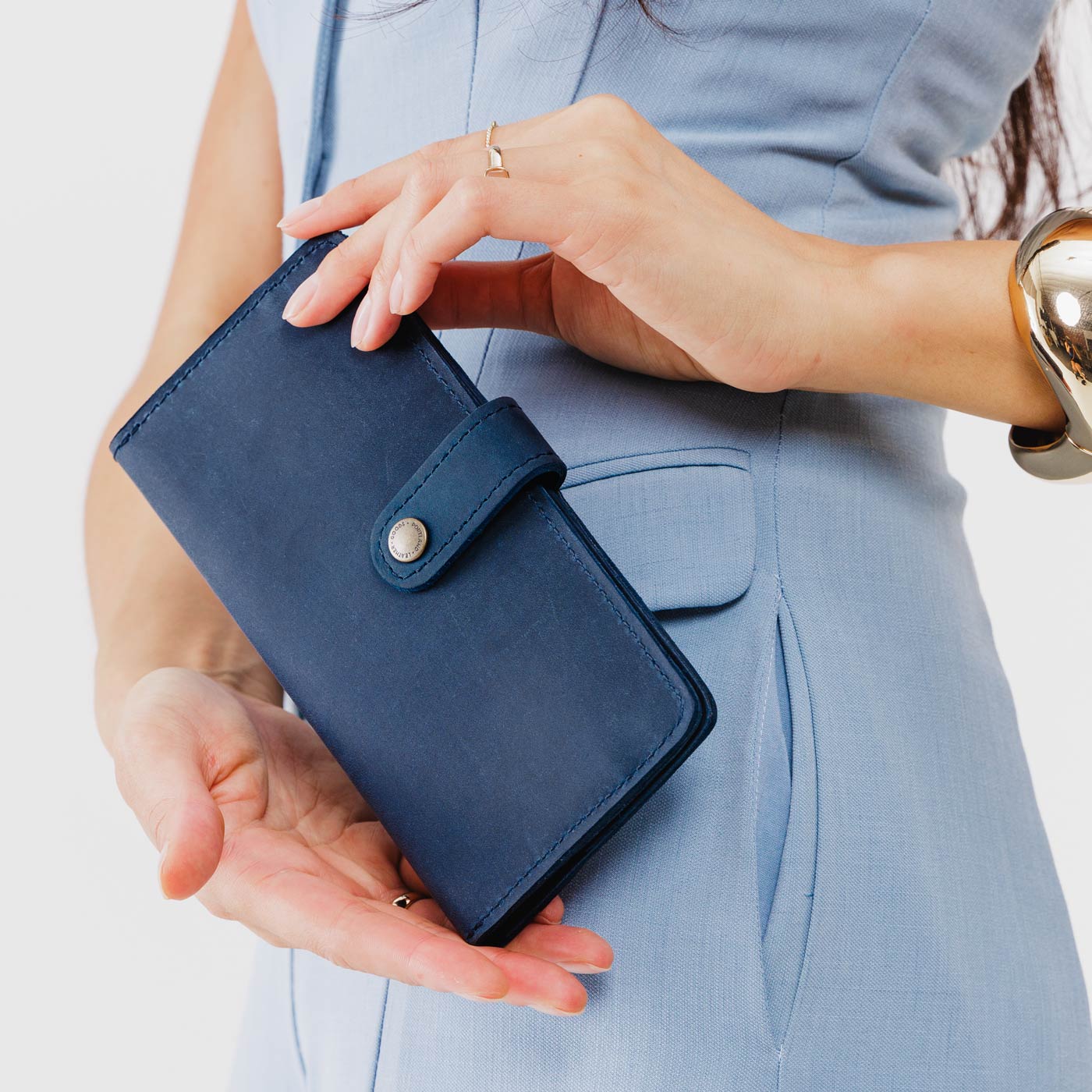 Deep Water | Model holding flowers and leather wallet with snap closed