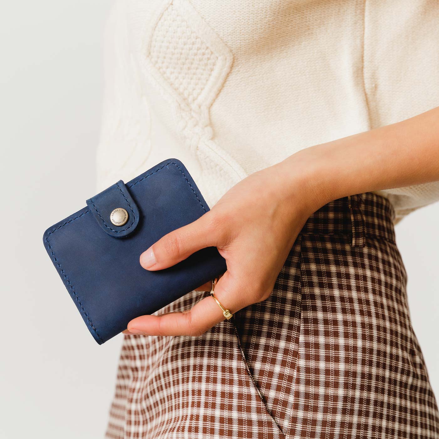 Deep Water | Model holding small leather bifold wallet with snap closed