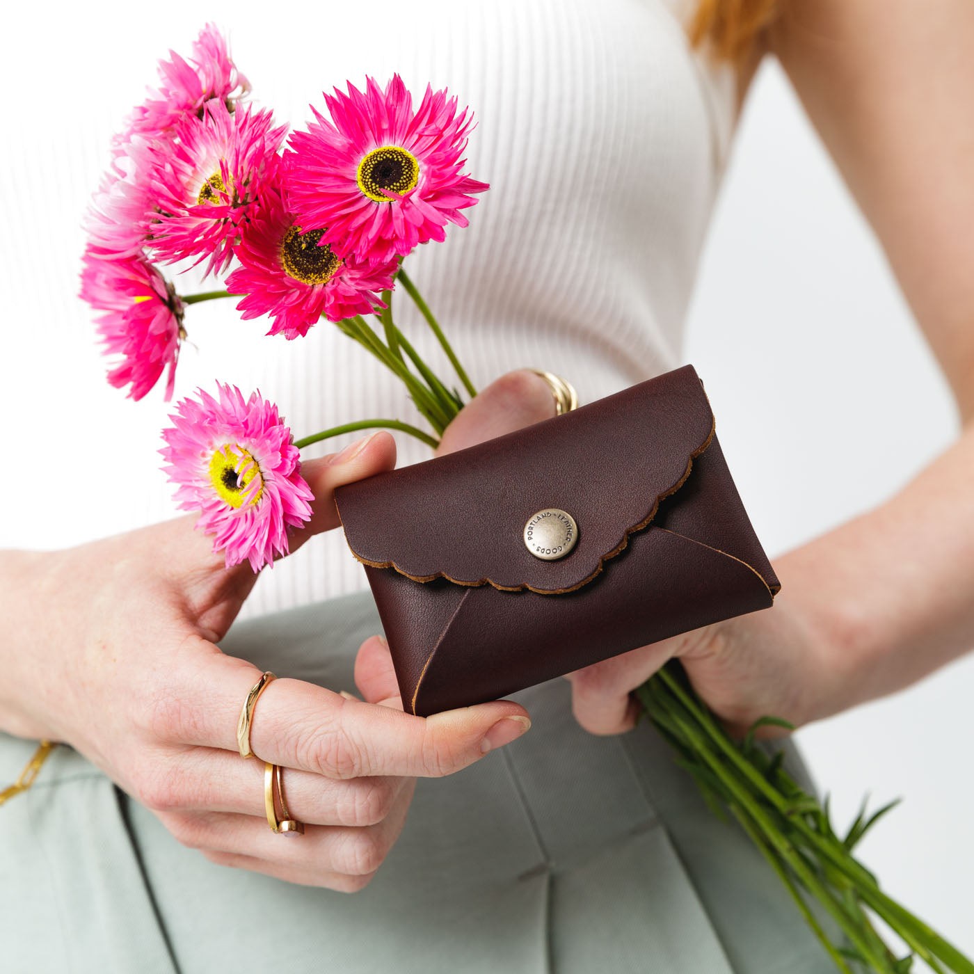 Grizzly | Model holding flowers and small leather wallet with scalloped edge