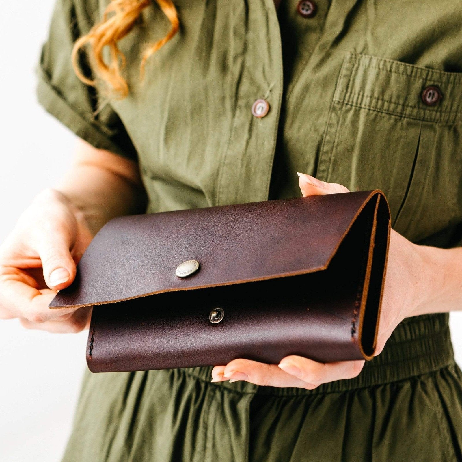 Cognac | Model holding leather wallet with snap closure slightly open